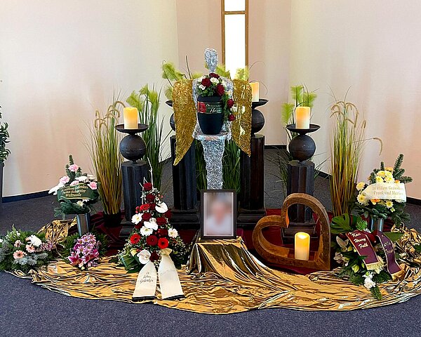 Urne auf Traueralter mit Blumenschmuck