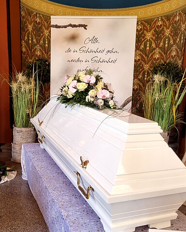 Sarg auf Traueralter mit Blumenschmuck