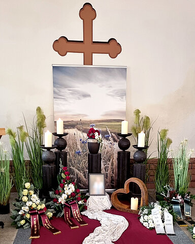 Urne auf Traueralter mit Blumenschmuck