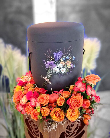 Urne auf Traueralter mit Blumenschmuck